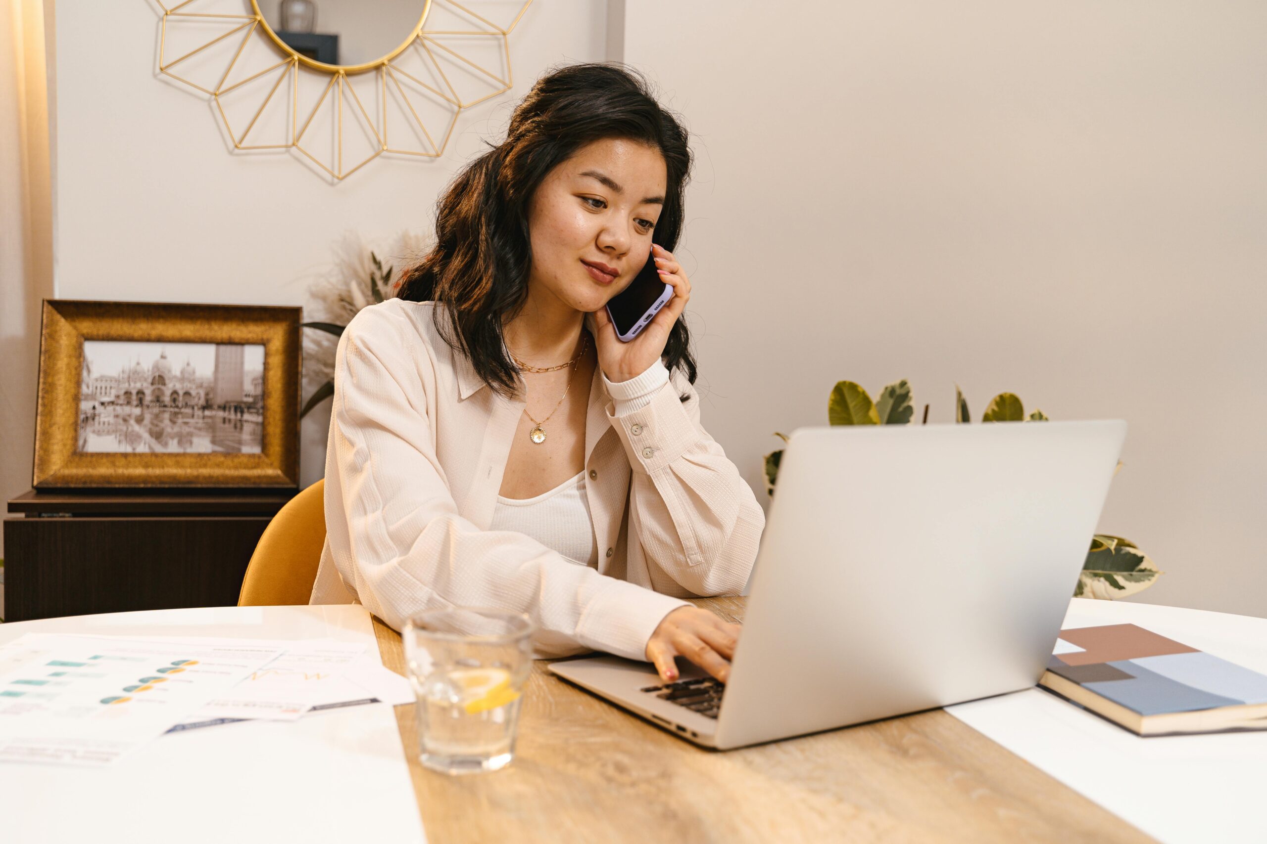 Woman working on the computer talking on the pgone